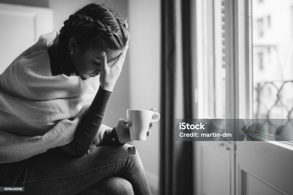 Depressed woman at home Unhappy woman sitting at the bed with cup of tea Pregnant Stock Photo