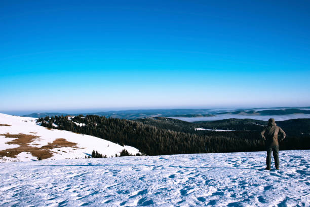 Man trekking in mountains in winter. Cold weather, snow on hills, winter hiking.