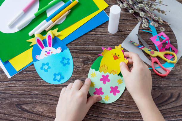 istock A child is holding an Easter egg gift with a chicken and Easter bunny toy. Handmade. Project of children's creativity, handicrafts, crafts for kids. 909675108