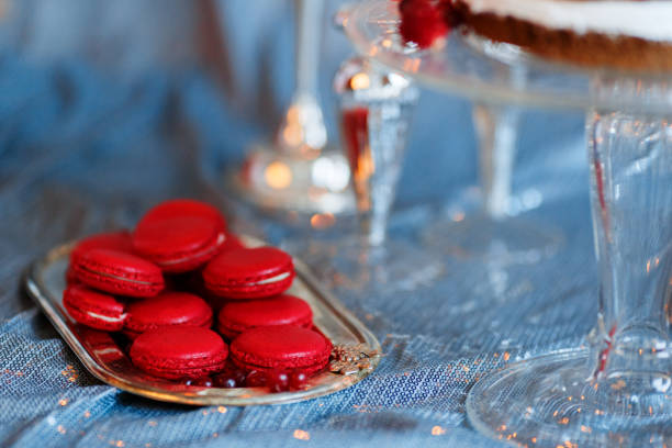 Rasperry macaroons , currant berries on a tray on red table