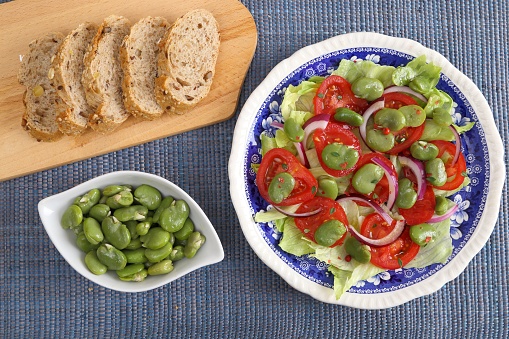 Close up of a broad beans salad with tomato and red onion.