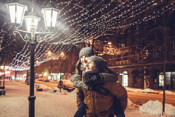 istock Young couple having fun under holiday winter illumination at night 909695114
