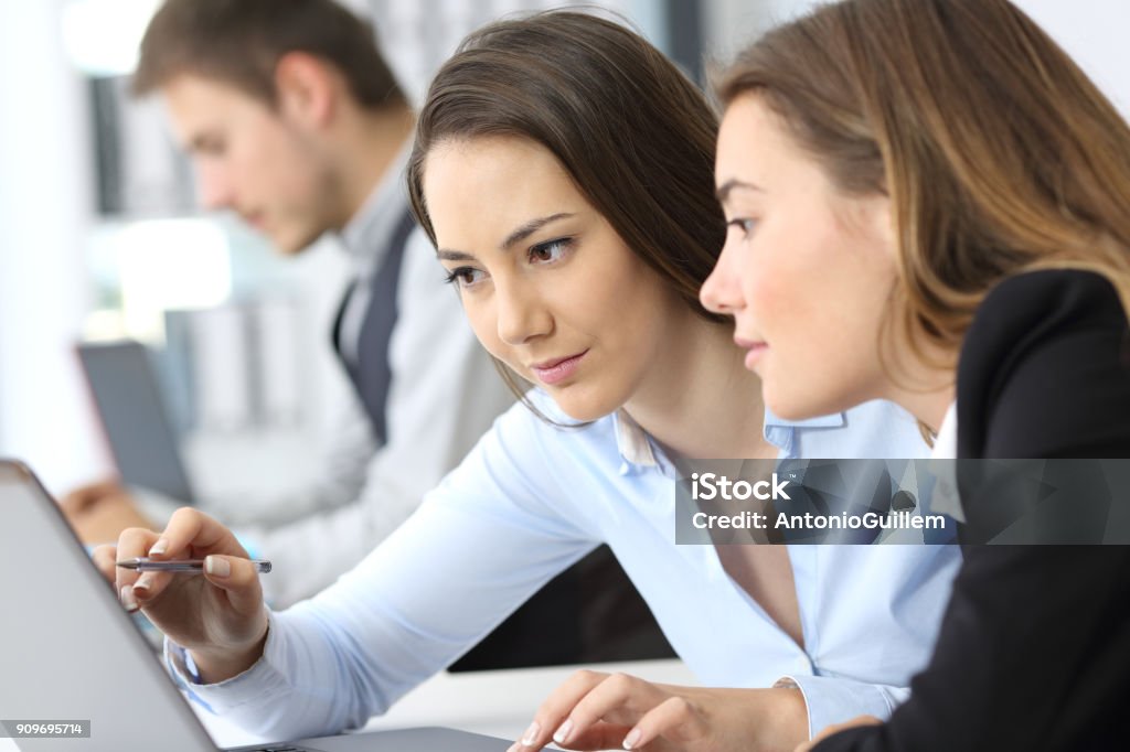 Businesswomen working on line together Two businesswomen working on line together with a laptop at office Office Stock Photo