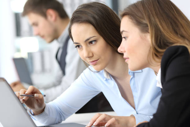 Businesswomen working on line together Two businesswomen working on line together with a laptop at office coordination photos stock pictures, royalty-free photos & images