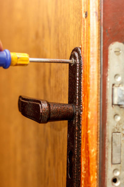 istock Locksmith making installation of door lock with screwdriver. 909700968
