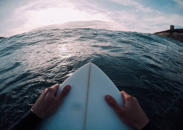 istock Surfer holding a surfboard in the sea closeup (point of view) 909701196