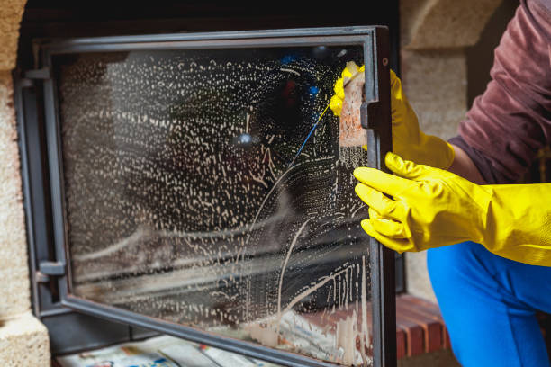 Hands in yellow gloves wash glass fireplace door stock photo