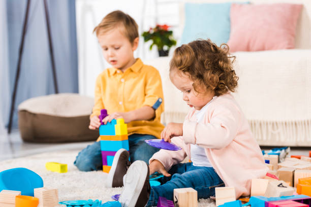 istock adorable siblings playing on a floor with plastic blocks 909704842