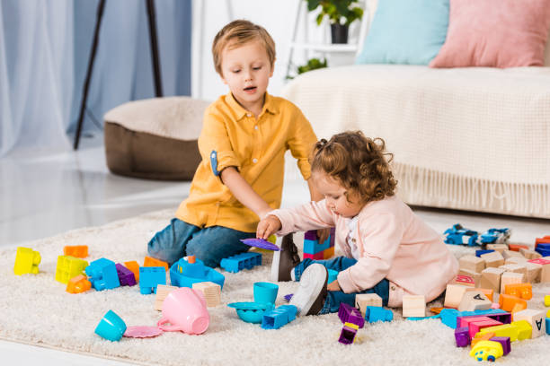 istock adorable siblings playing with plastic blocks on floor 909705068