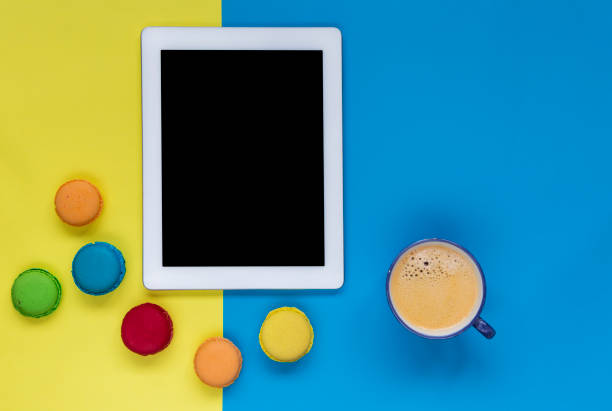 istock Digital Tablet with coffee and colorful macaroons on color block background 909714842