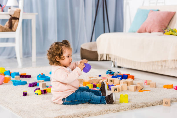 istock side view of adorable kid playing with plastic blocks on floor 909725804