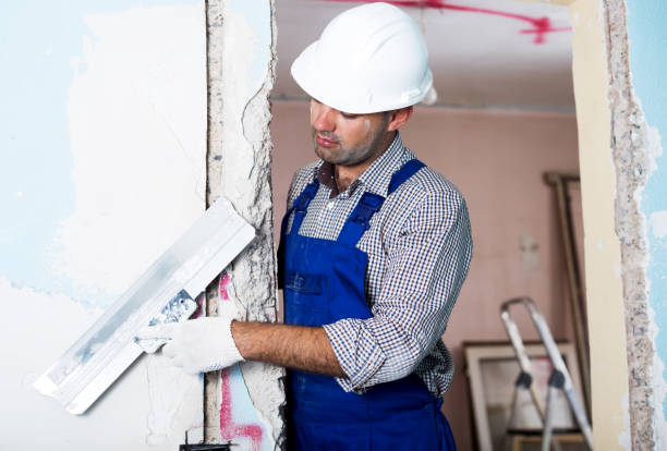 istock Repairman in helmet plastering wall with putty 909742164