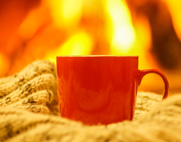 istock Orange mug for tea or coffee, wool things near cozy fireplace, winter vacations, selective focus.