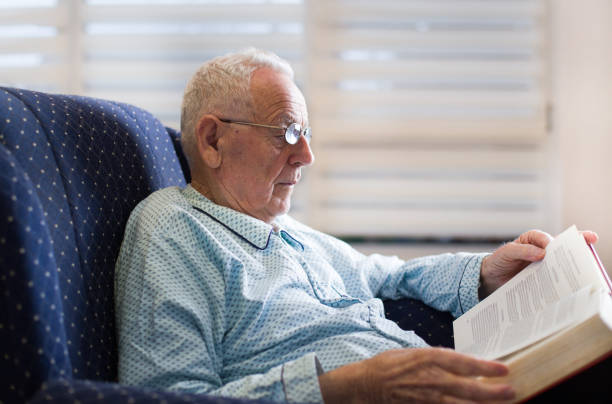 istock Old man reading book in armchair 909761334