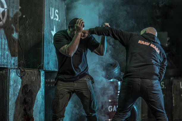 istock Two men using Krav Maga fighting style during disarmament in dark indoor urban setting 909761576