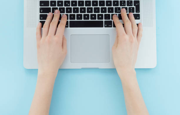 istock hands typing on silver laptop on blue minimalist background, flat lay, business concept 909768080