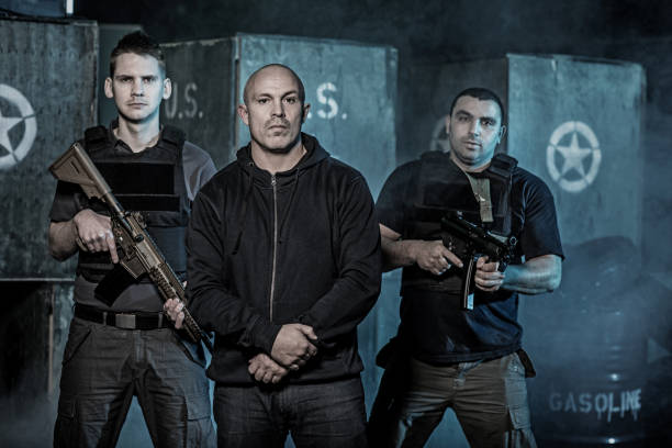istock Krav Maga fighting group posing with weapons for team picture during training in dark indoor urban setting 909768156