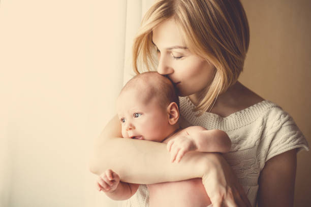 nowo narodzone dziecko w czułym uścisku matki przy oknie - mother baby new new life zdjęcia i obrazy z banku zdjęć