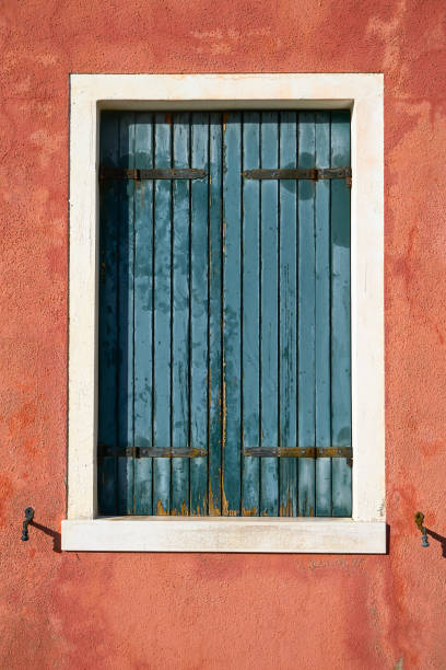 istock Window with closed green shutter on red wall. Italy, Venice, Burano island. 909778088
