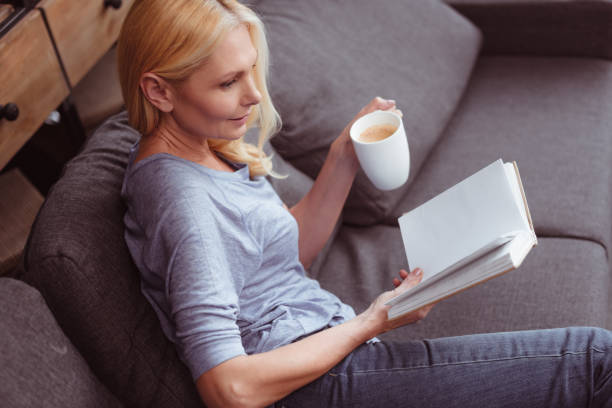 istock woman with book and coffee at home 909795438