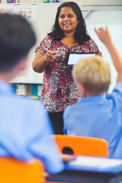 insegnante di scuola elementare aborigena che dà una presentazione alla classe. gli studenti hanno le mani alzate per fare domande in classe - top of the class foto e immagini stock