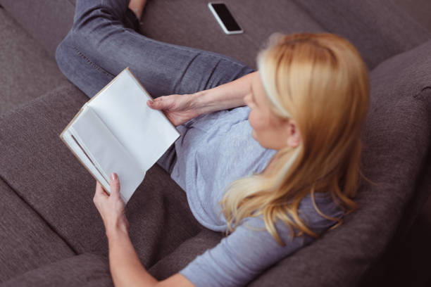 istock woman reading book at home 909798572