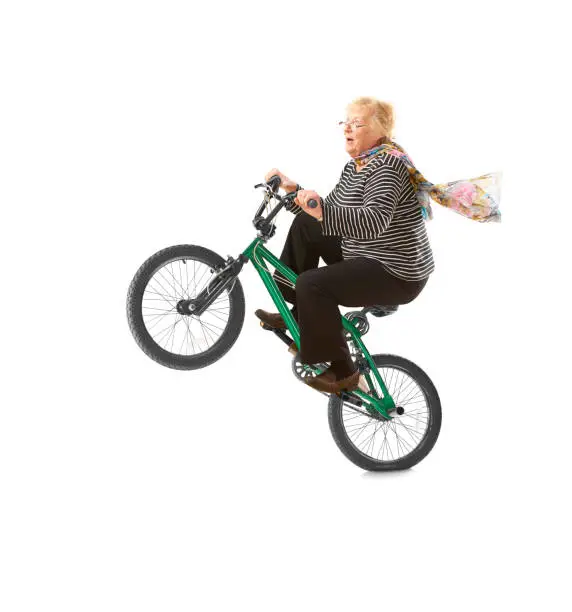 a senior lady pulls a wheelie on a box bike on a white background