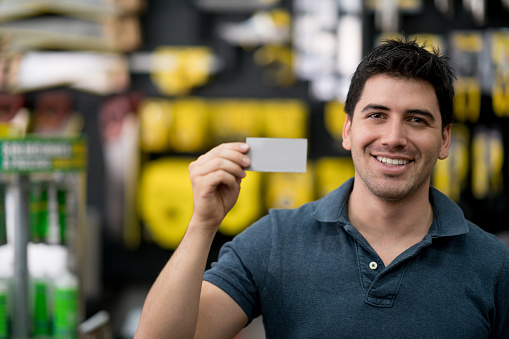 Portrait of happy man holding a business card at a hardware store