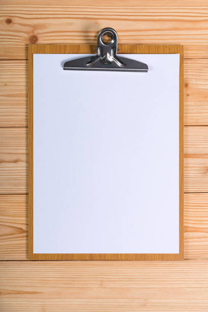 istock clipboard with blank white paper sheet on wood table top view with copy space. 909806348