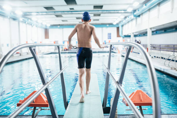 chłopiec w basenie na desce nurkowej - diving board zdjęcia i obrazy z banku zdjęć