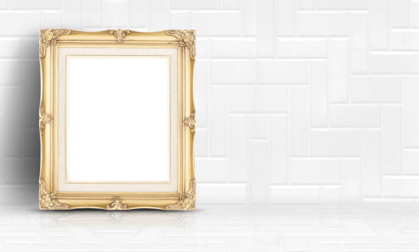 istock Empty golden vintage frame at white clean tile wall and floor background,Minimal simple style interior backdrop.mock up space for adding your text or design in banner. 909818316