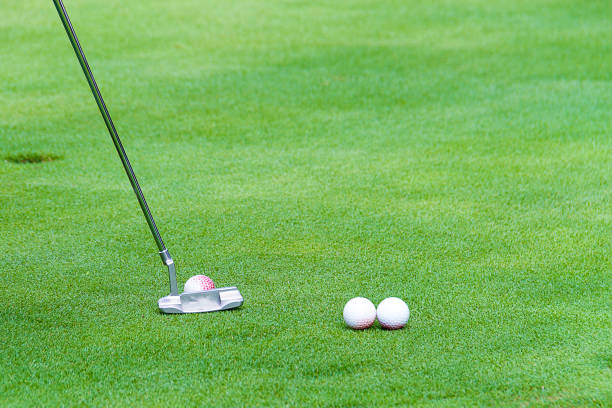istock Golf ball behind putter on green 909818548