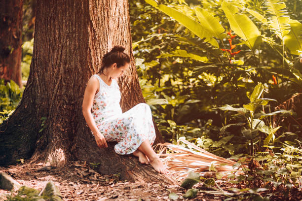 istock Young woman lying by the tree 909828306