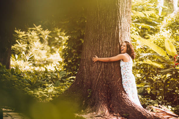 jovem mulher abraçando a árvore - abraçar árvore - fotografias e filmes do acervo