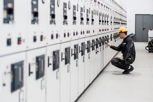 Maintenance engineer testing medium voltage switchgear and bay control unit. Relay protection system