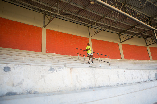 A young black man does some stair running at the local stadium as part of his training