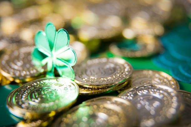 Horizontal view of a hand holding a freshly picked four leaf clover, a natural green good luck charm associated with Irish culture and St. Patrick's Day. 