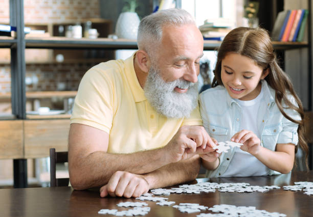 istock Grandfather and girl chatting while playing jigsaw puzzle 909847558