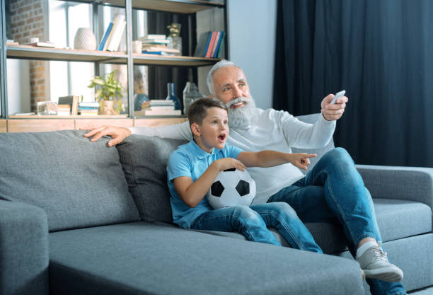 istock Emotional kid watching tv with grandfather 909848078