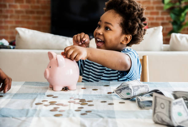 Black boy collecting money to piggy bank Black boy collecting money to piggy bank science and technology kids stock pictures, royalty-free photos & images