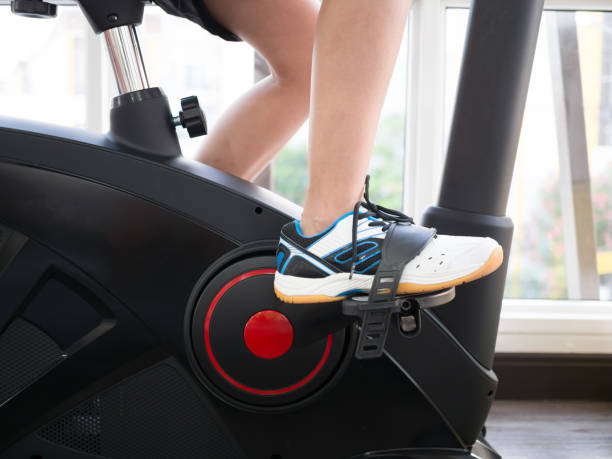 istock A woman is exercising on gym bicycle. 909865690