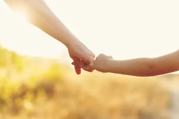Family values. The father holds his daughter's hand. Hand in hand. Child support. Walk at sunset.