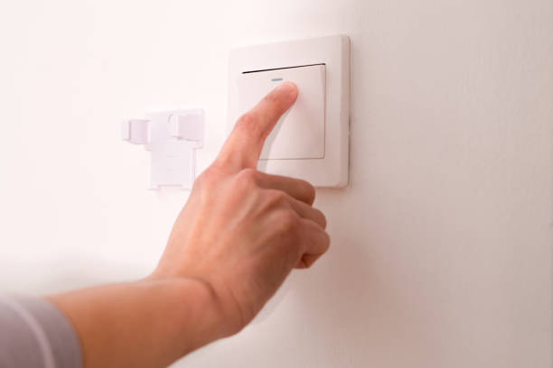 istock turning off/on the wall-mounted electric light switch. 909866668