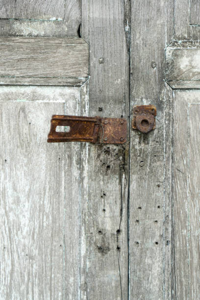 istock Security breach concept with closeup and copy space on an old rusty metal key lock installed on wood door with crack. 909866980