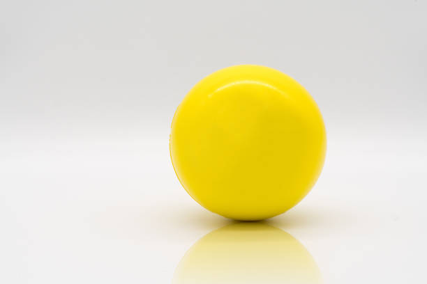 Yellow stress ball rolling on reflection floor isolated on white background. stock photo