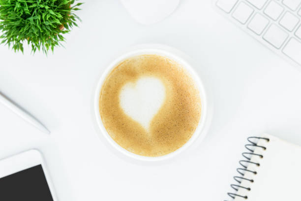 istock A latte coffee with art heart milk on the white desk table from top view and copy space. Flat lay with desk, business and valentine concept. 909867620
