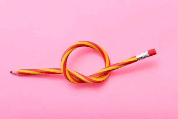 Flexible pencil on a pink background. Bent pencils two-color