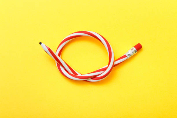 istock Flexible pencil on a yellow background. Bent pencils two-color 909871508