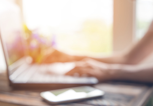 Female hands on laptop, defocused photo close up with sun light