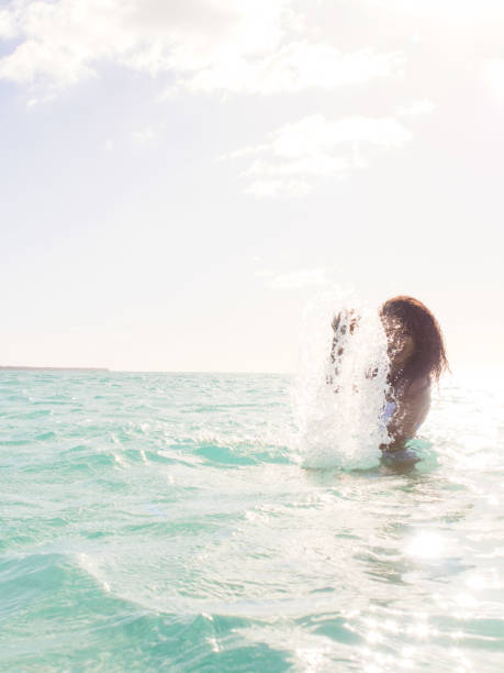 Copy space shot of cheerful young woman splashing sea water. Photo was taken in Caribbean sea, Isla Saona, Dominican Republic.